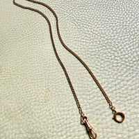 Gold chain necklace on a textured light green background