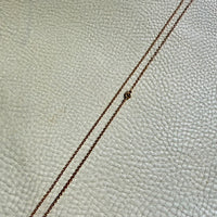 Gold chain necklace on a textured beige surface