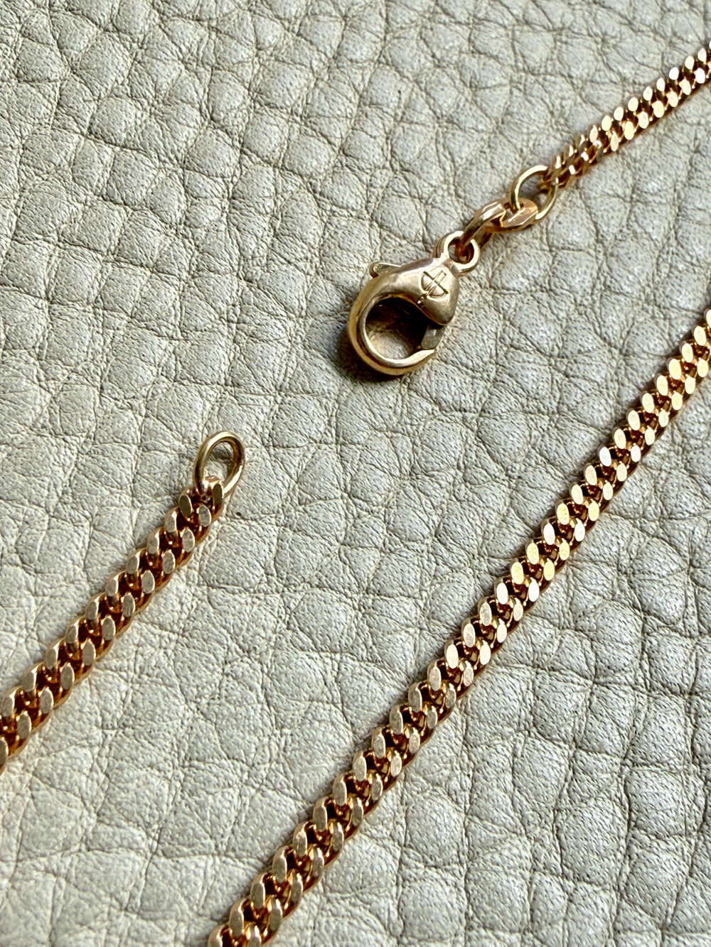 18k Gold curb chain necklace on a textured light surface
