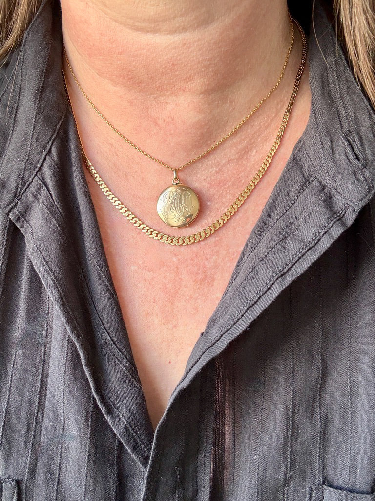Close-up of a person wearing a gold necklace with a pendant.