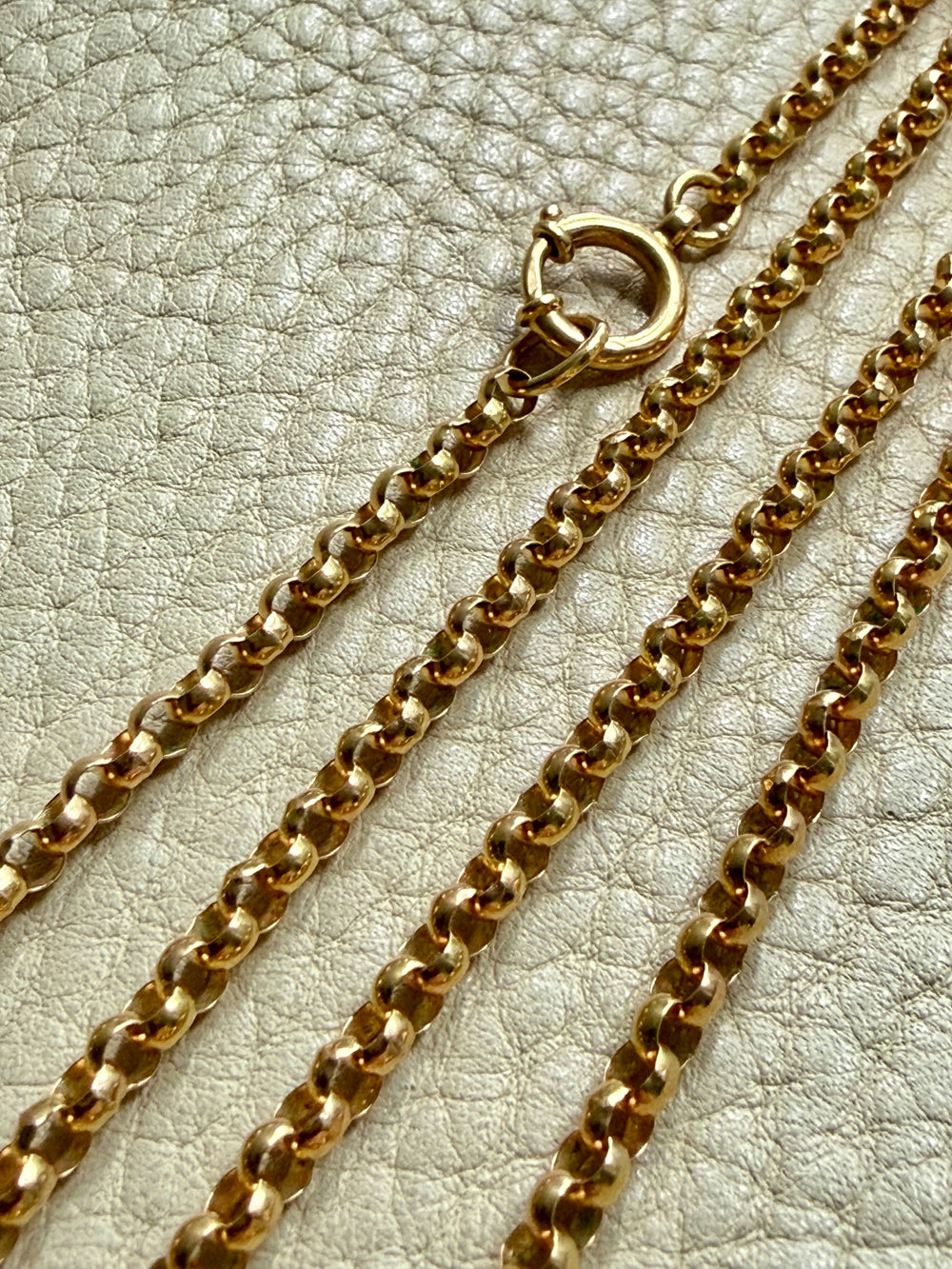 Gold chain necklace on a textured beige surface
