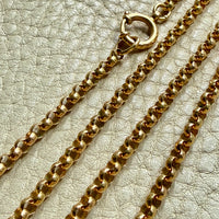 Gold chain necklace on a textured beige surface