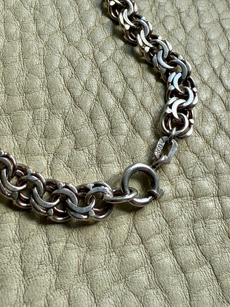 Silver chain bracelet on a textured green surface