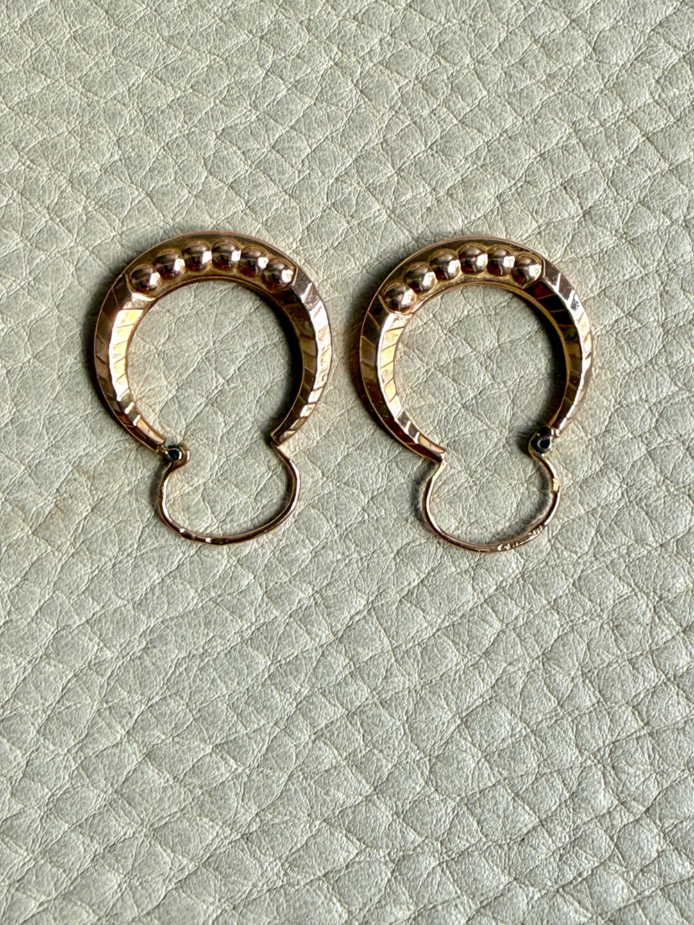Pair of French vintage 18k Gold hoop earrings on a textured light gray surface