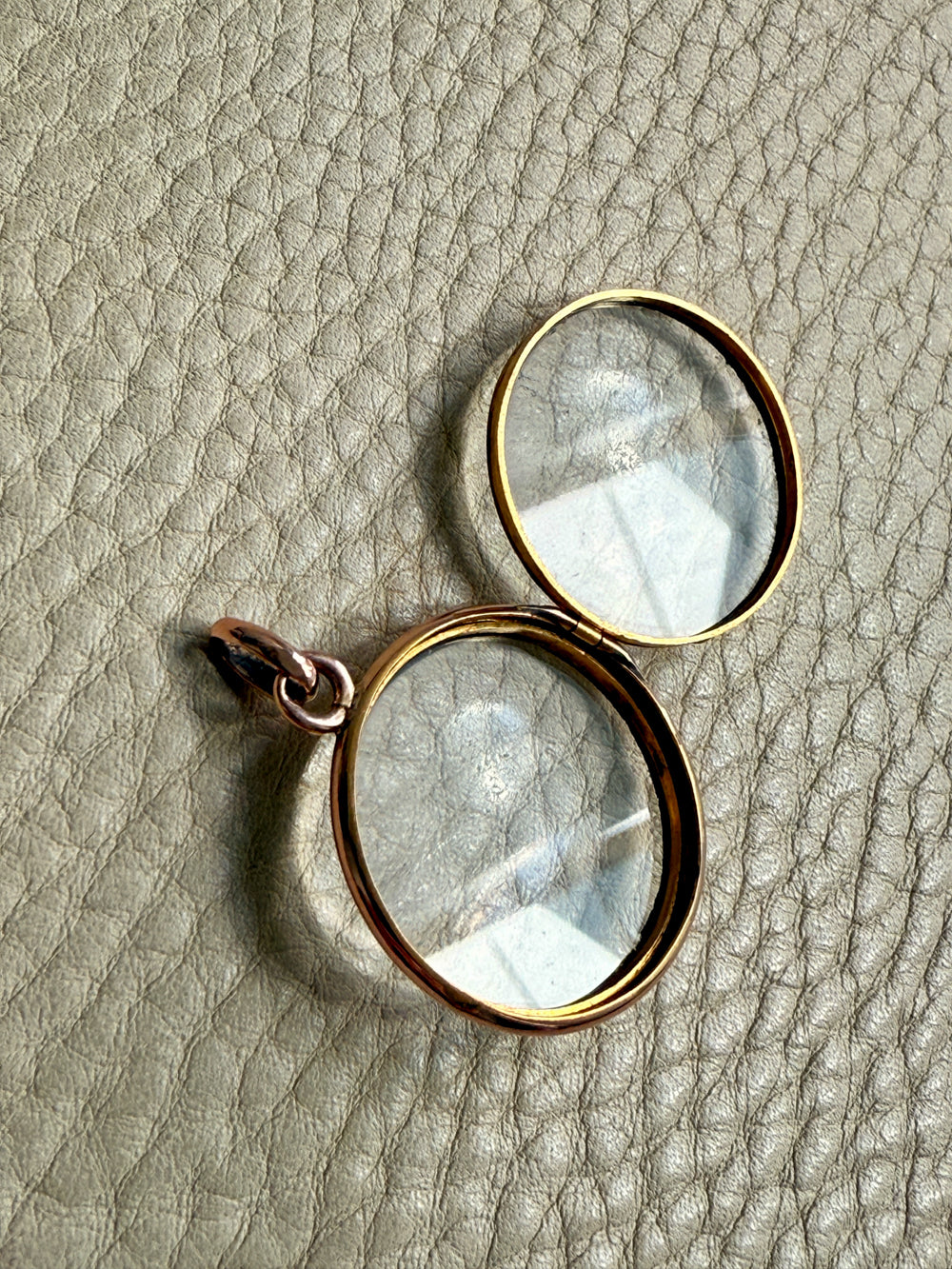 glass locket with gold frames on a textured beige surface