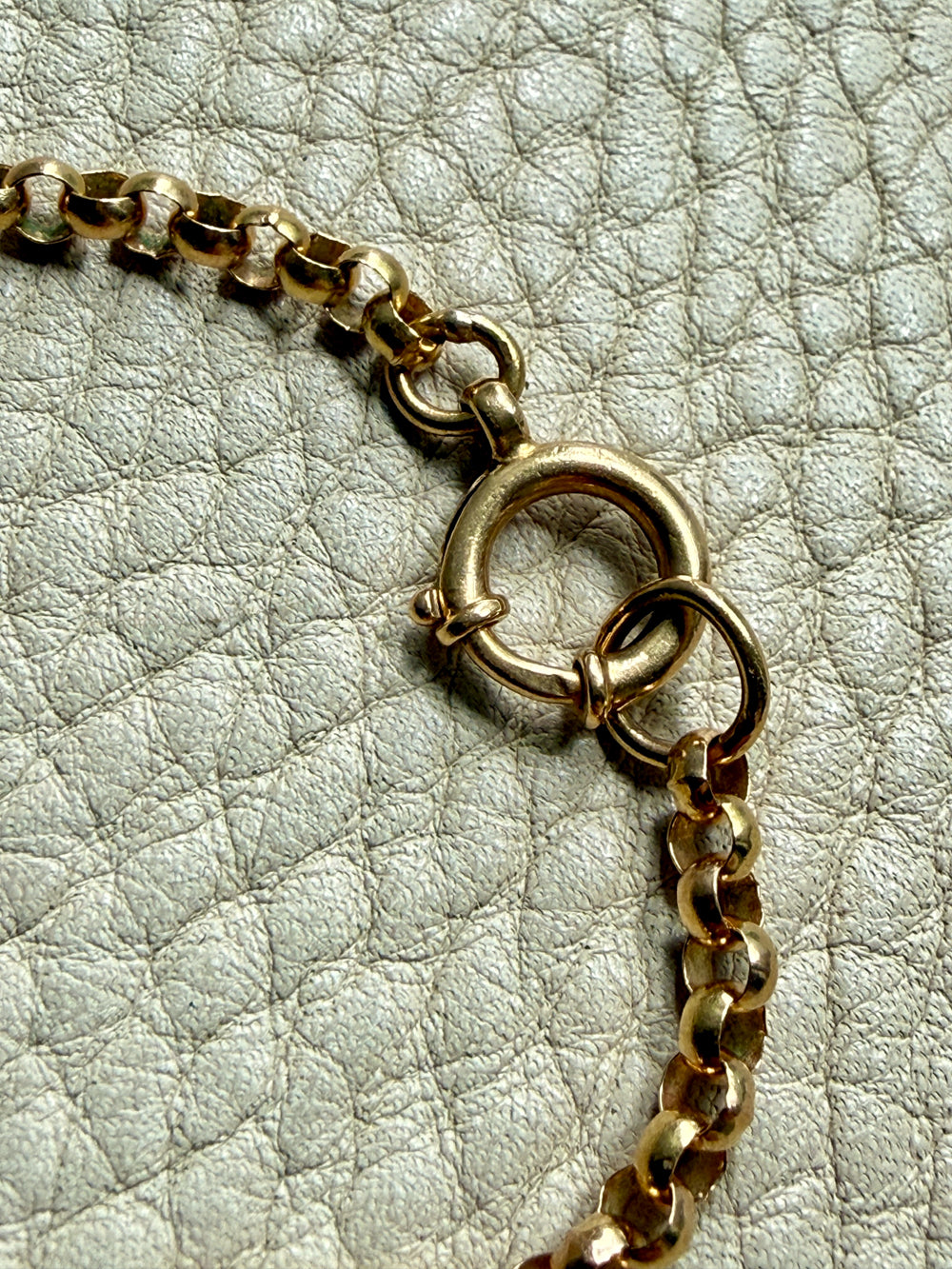 18k Gold antique rolo link necklace clasp detail on a textured light gray surface