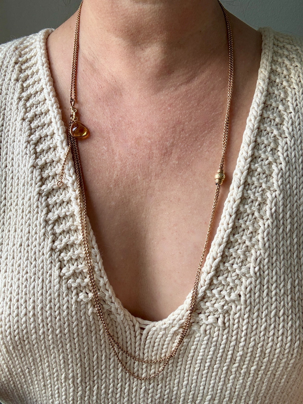 antique 18k gold Necklace with pendant worn by a person in a beige knit sweater.