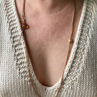 antique 18k gold Necklace with pendant worn by a person in a beige knit sweater.