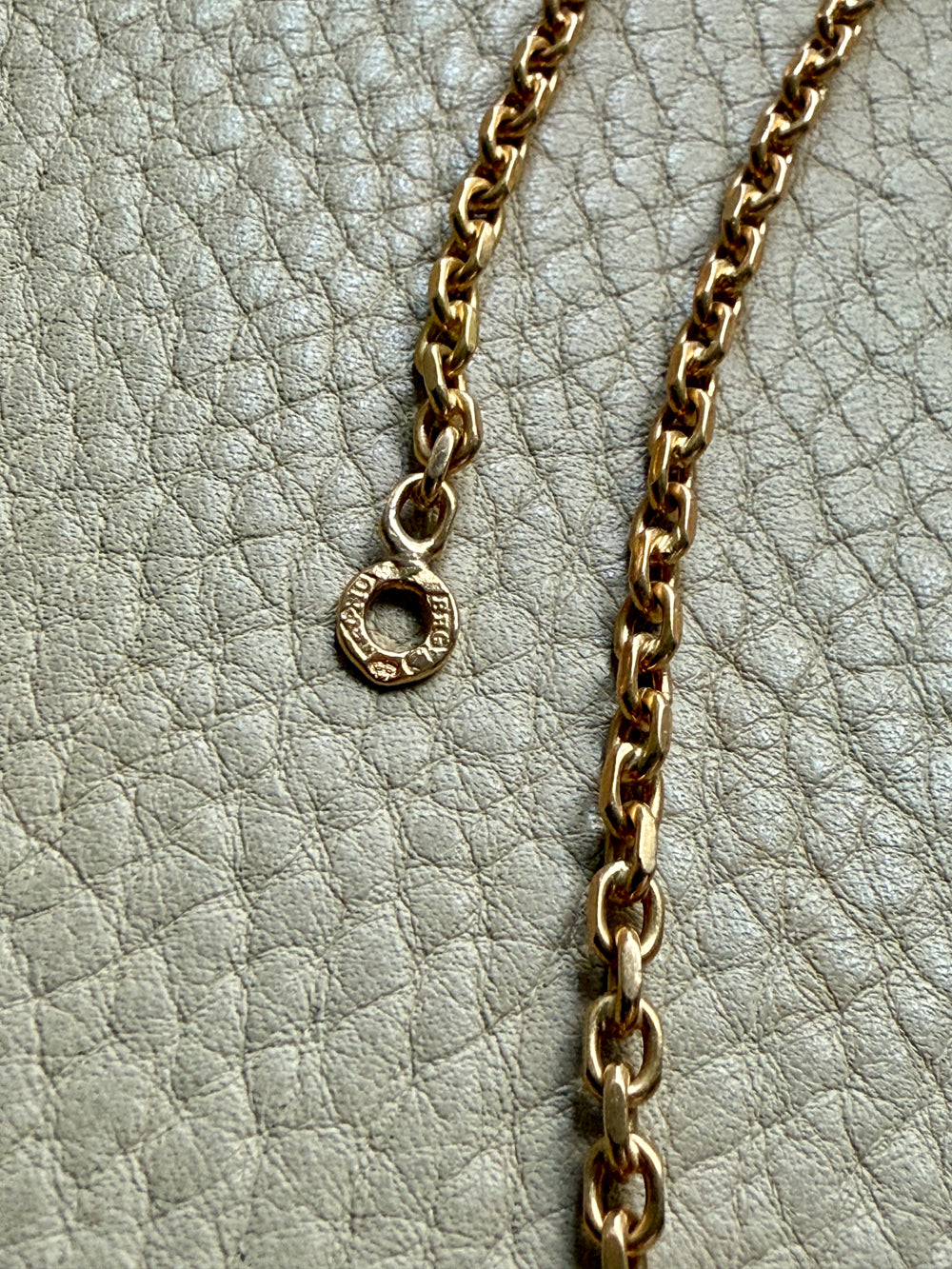 Gold chain necklace with hallmarks on a textured gray surface