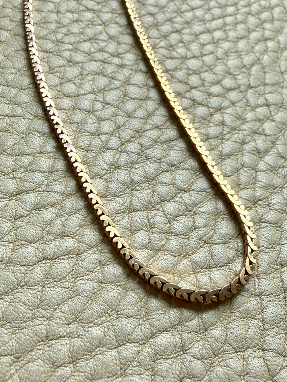 Gold chain necklace on a textured light gray surface