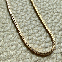 Gold chain necklace on a textured light gray surface