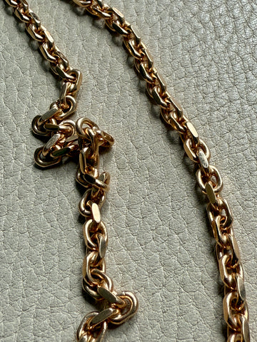 Gold chain necklace on a textured light gray background
