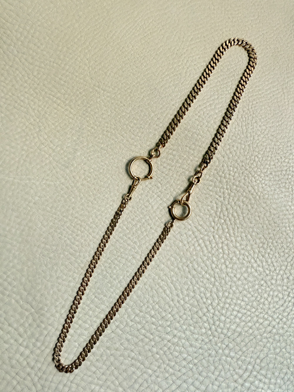 Gold chain necklace on a textured beige background