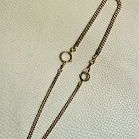 Gold chain necklace on a textured beige background