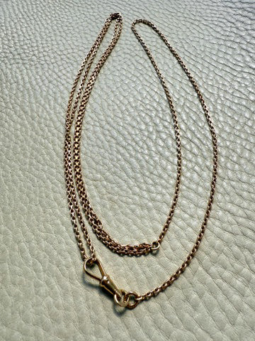 Gold chain necklace on a textured light green surface