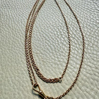 Gold chain necklace on a textured light green surface