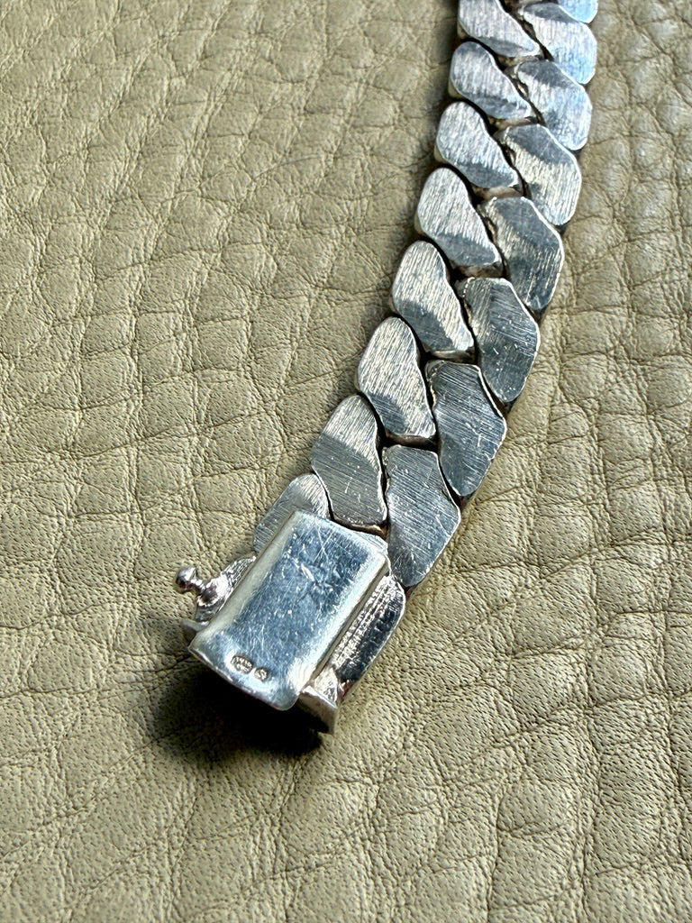 Silver chain bracelet on a textured beige surface