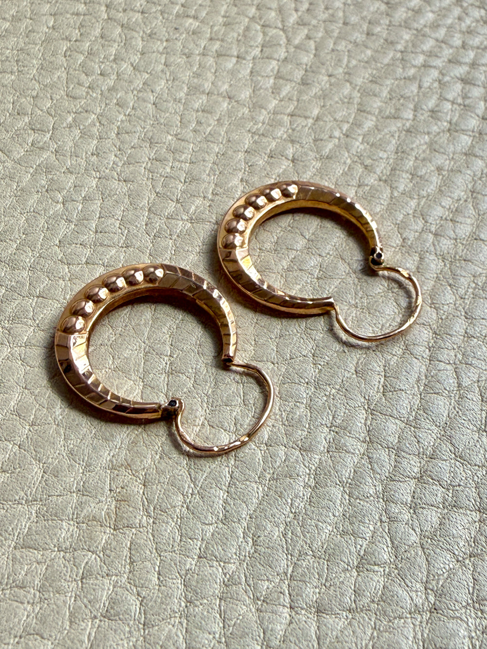 Pair of French vintage 18k Gold hoop earrings on a textured light gray surface