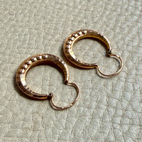 Pair of French vintage 18k Gold hoop earrings on a textured light gray surface