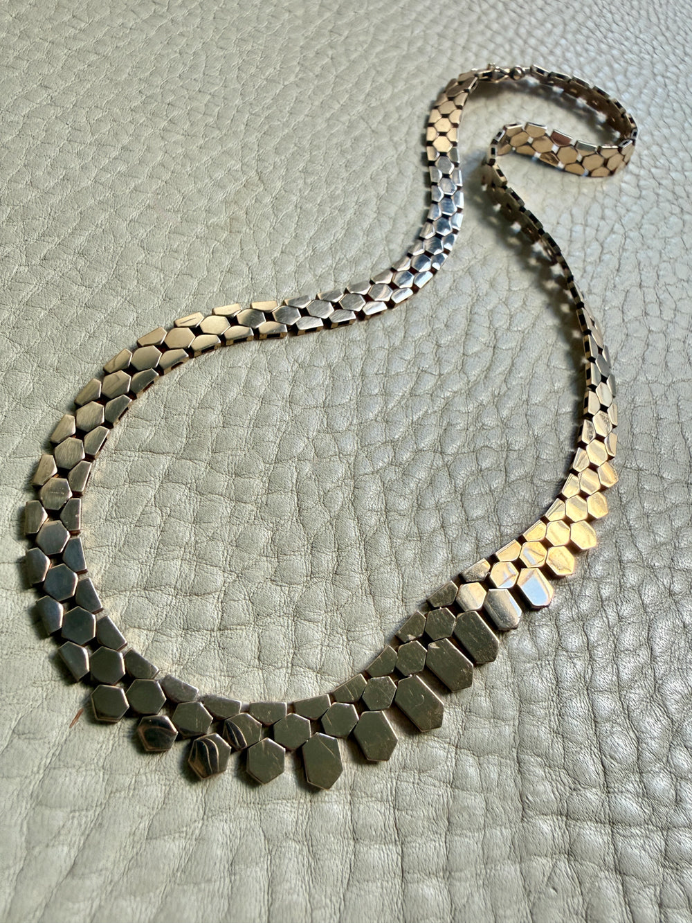 Necklace with hexagonal links on a textured surface