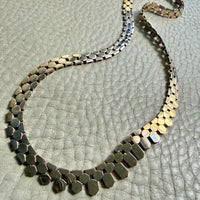 Necklace with hexagonal links on a textured surface