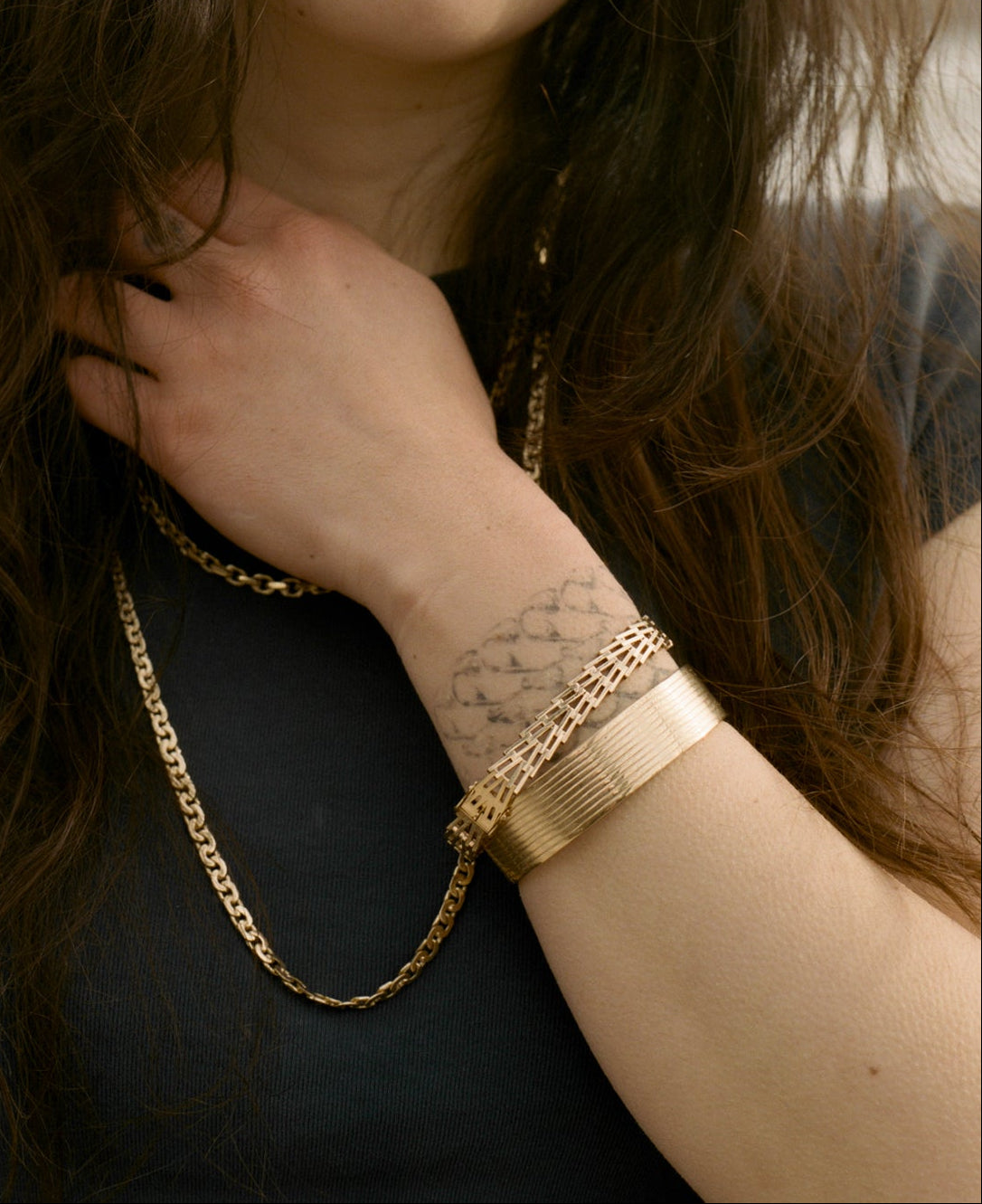 Woman wearing gold jewelry outdoors with a blurred background