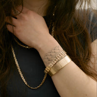 Woman wearing gold jewelry outdoors with a blurred background