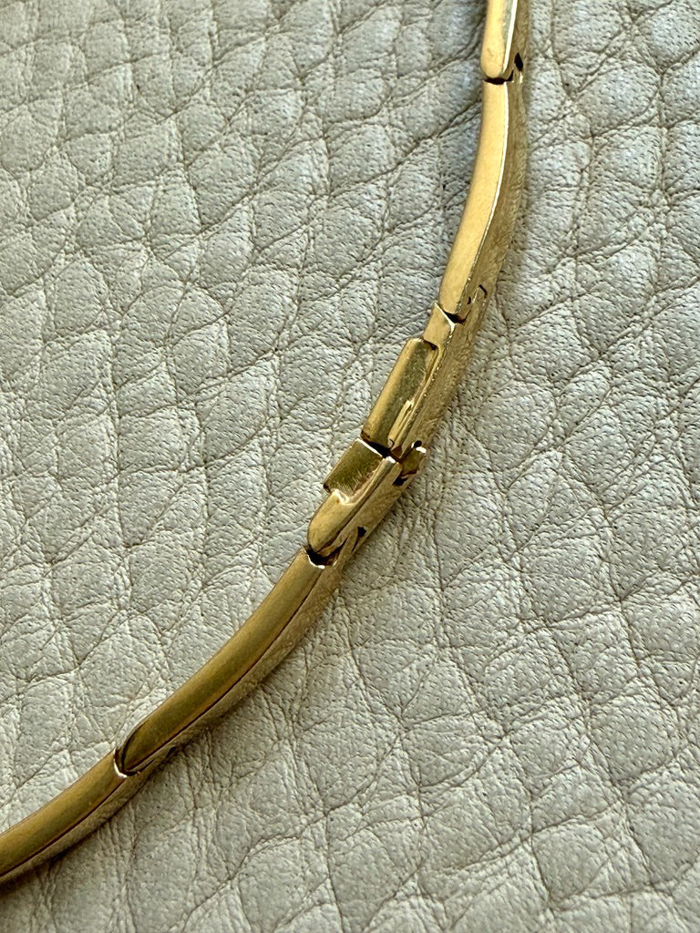 Gold bracelet on a textured light gray surface
