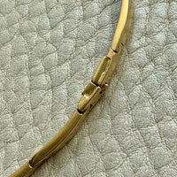 Gold bracelet on a textured light gray surface