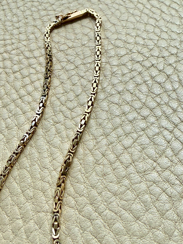 Gold chain on a textured beige surface