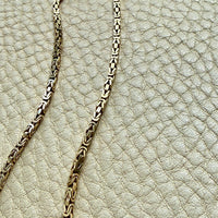 Gold chain on a textured beige surface