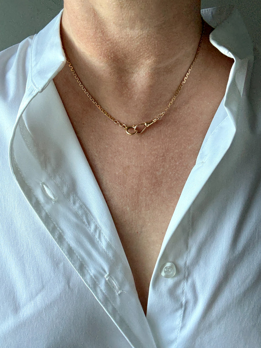 Person wearing a gold chain necklace with a white shirt.