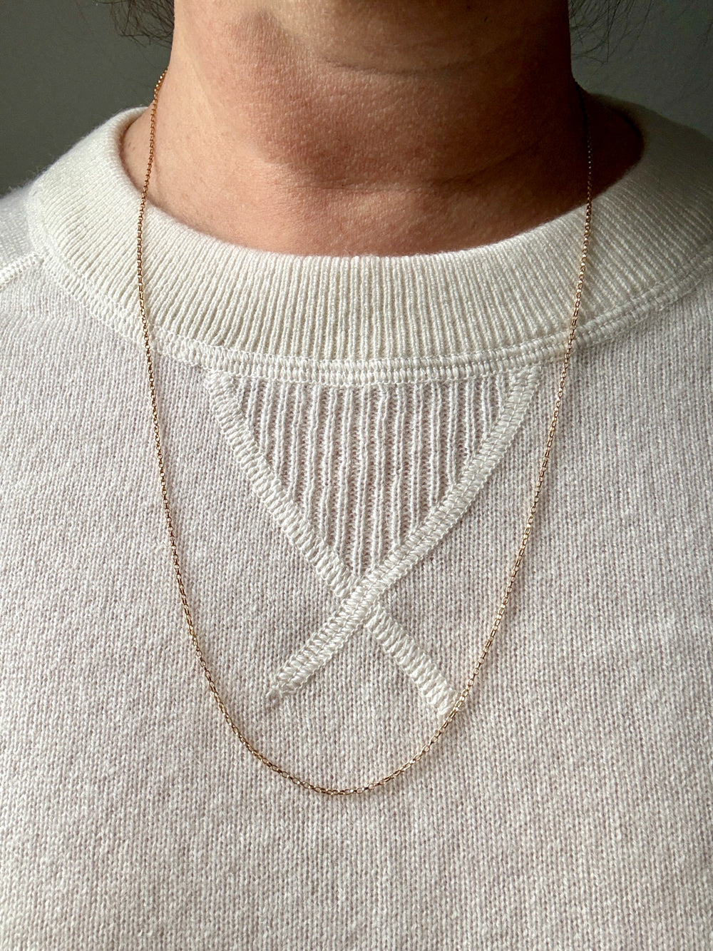 18k gold Necklace worn by a person on a light gray sweater