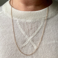 18k gold Necklace worn by a person on a light gray sweater