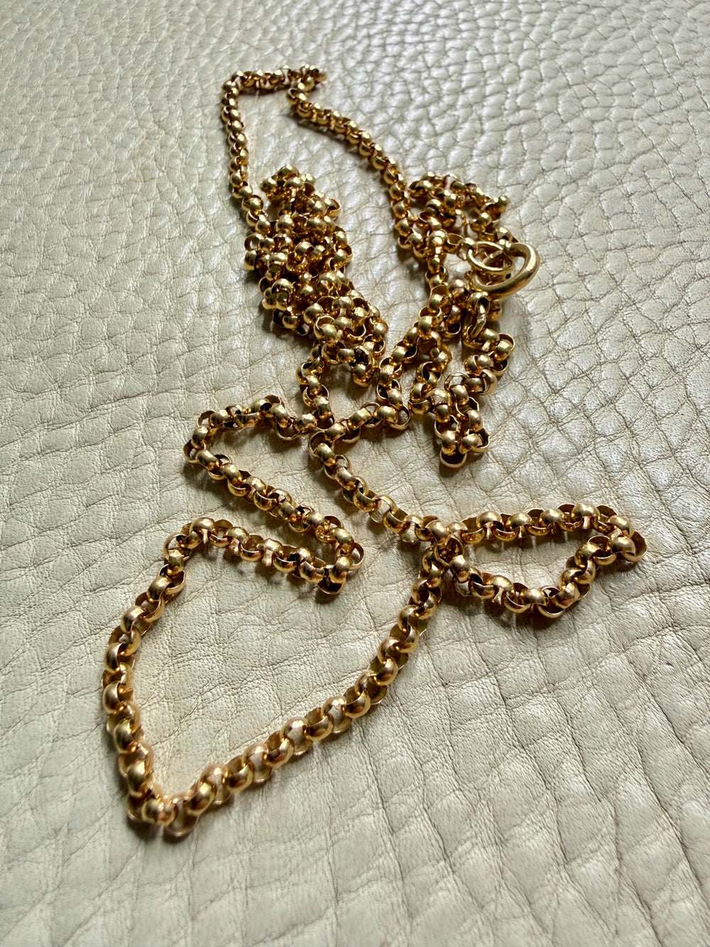 18k Gold antique rolo link necklace on a textured light gray surface
