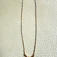 18k Gold and platinum watch chain with clip on a textured beige background