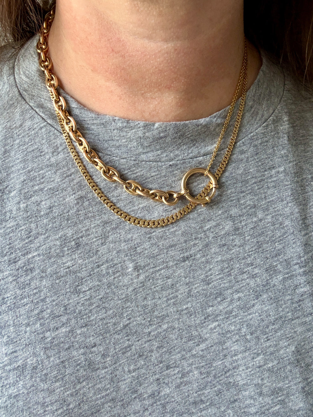 Gold chain necklaces on a person wearing a gray shirt