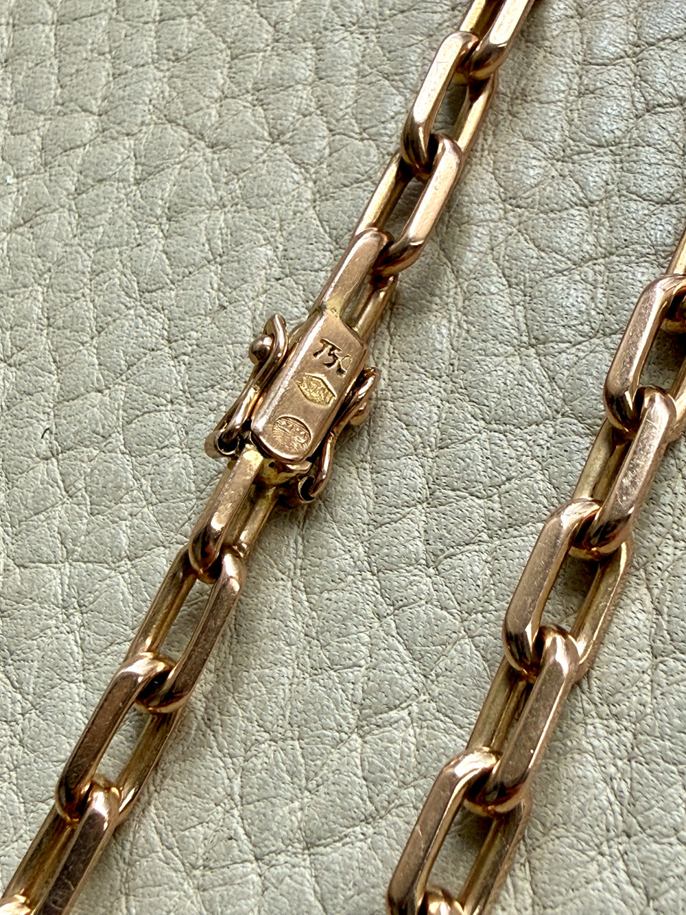 Close-up of a gold chain on a textured light green background