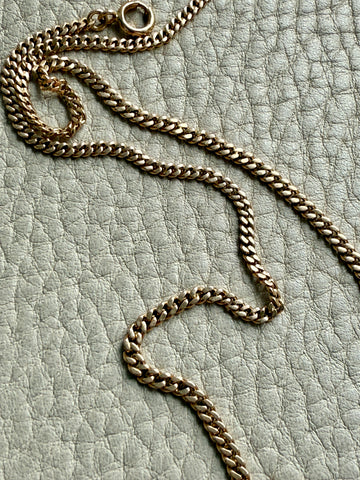 Gold chain necklace on a textured light gray surface