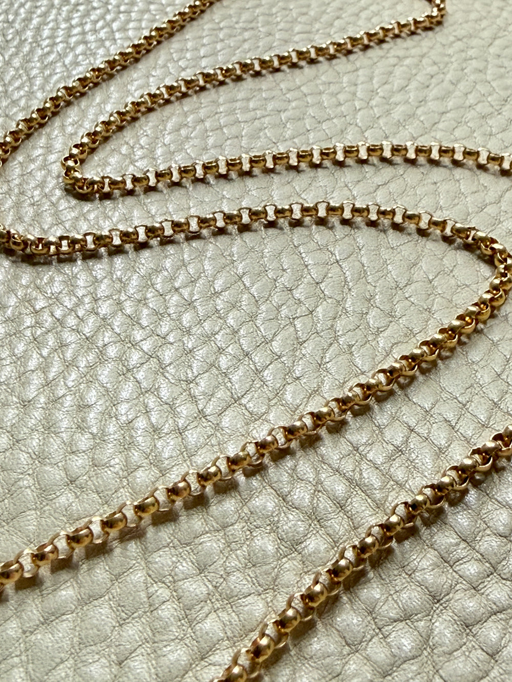 18k Gold antique rolo link necklace on a textured light gray surface