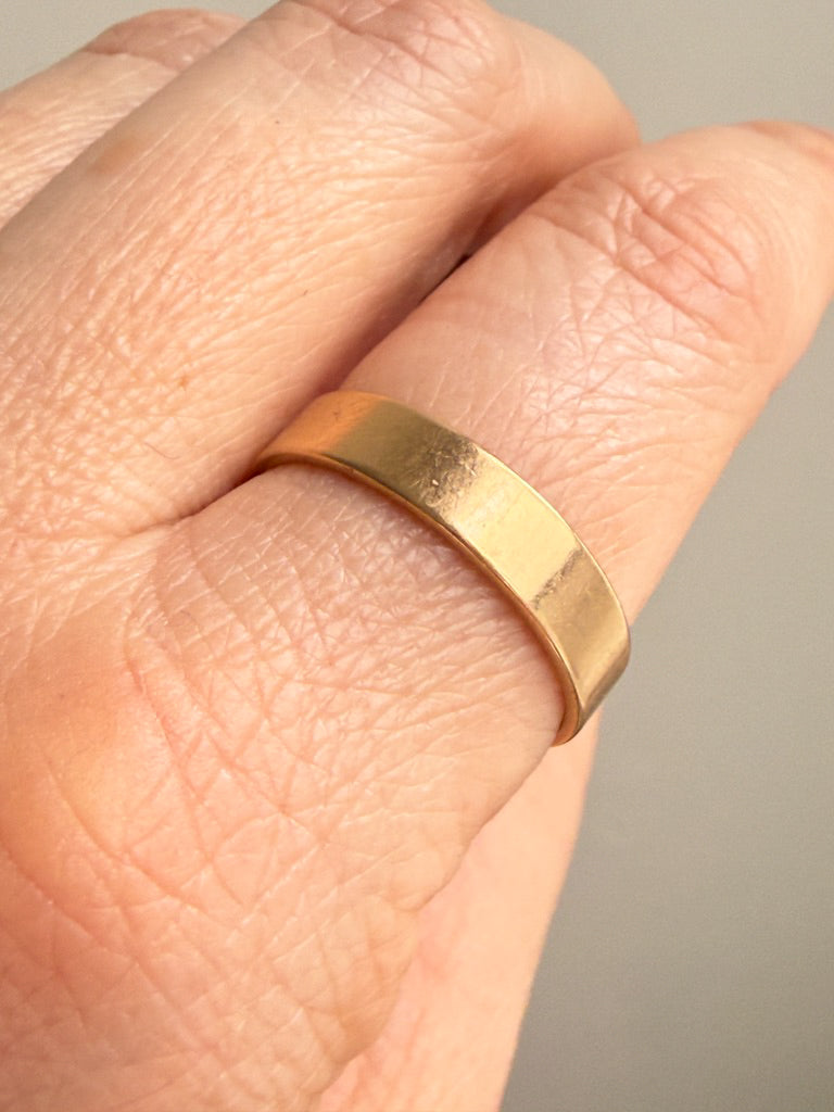 Gold ring on a person's finger with a neutral background