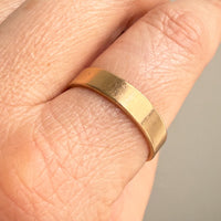 Gold ring on a person's finger with a neutral background