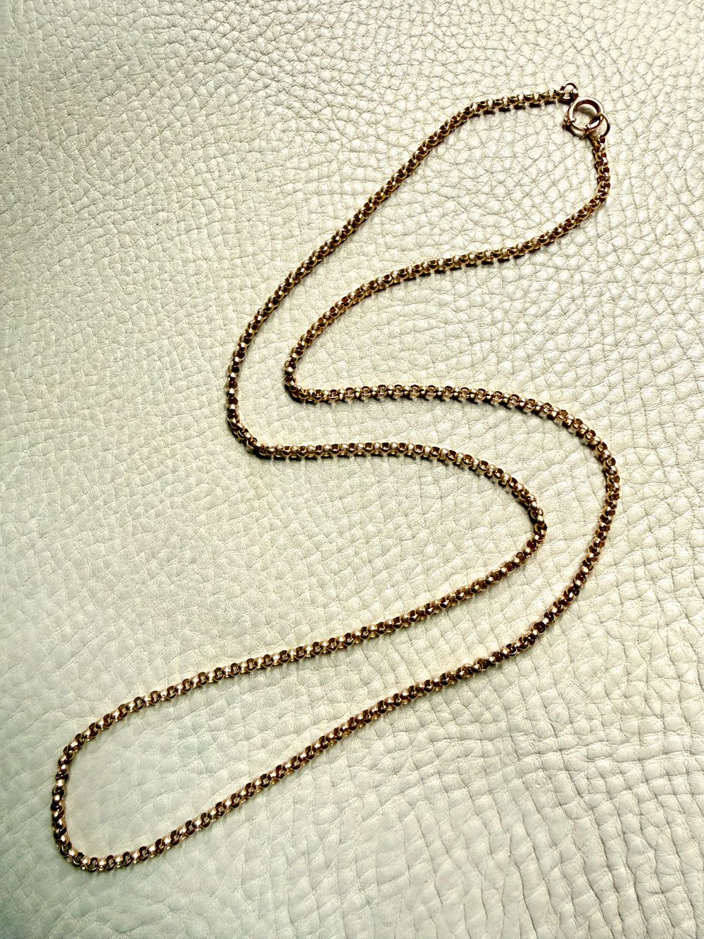 18k Gold antique rolo link necklace on a textured light gray surface