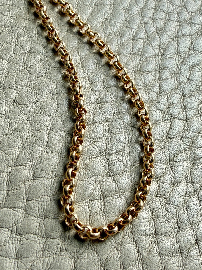 Gold chain necklace on a textured gray surface