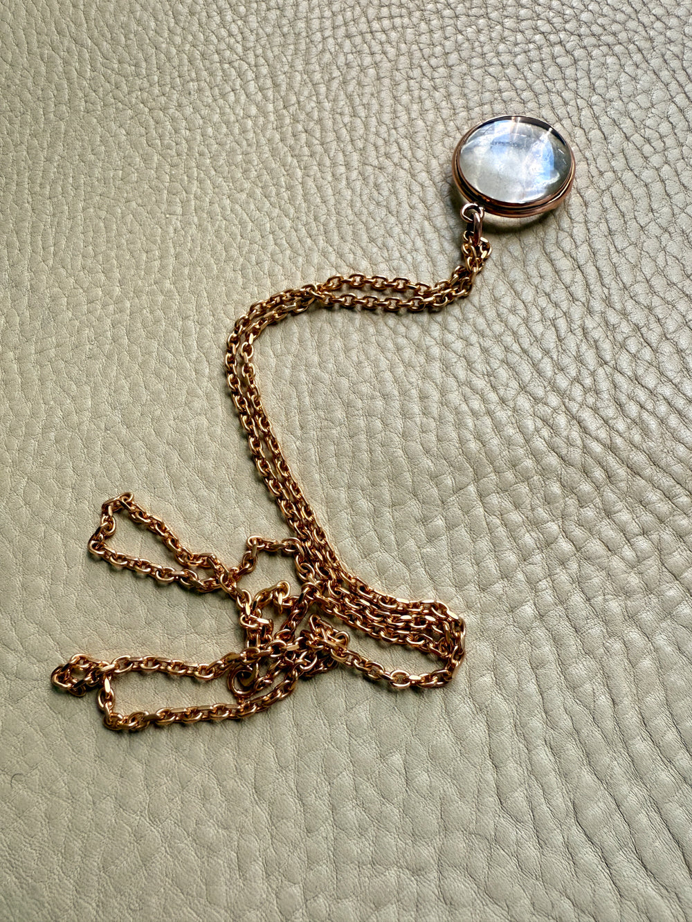 Necklace with a round pendant on a textured beige surface. Penelope Penelope vintage gold jewelry