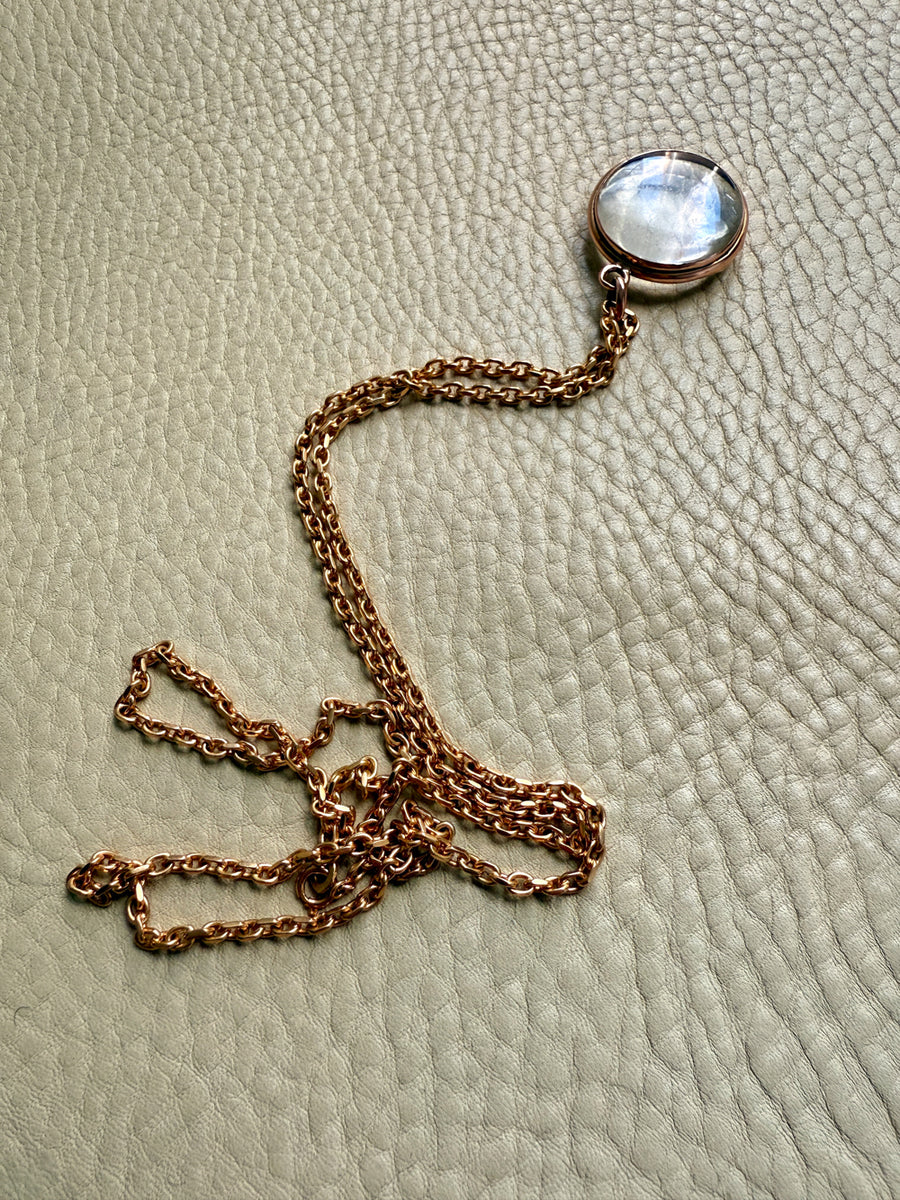 Necklace with a round pendant on a textured beige surface. Penelope Penelope vintage gold jewelry
