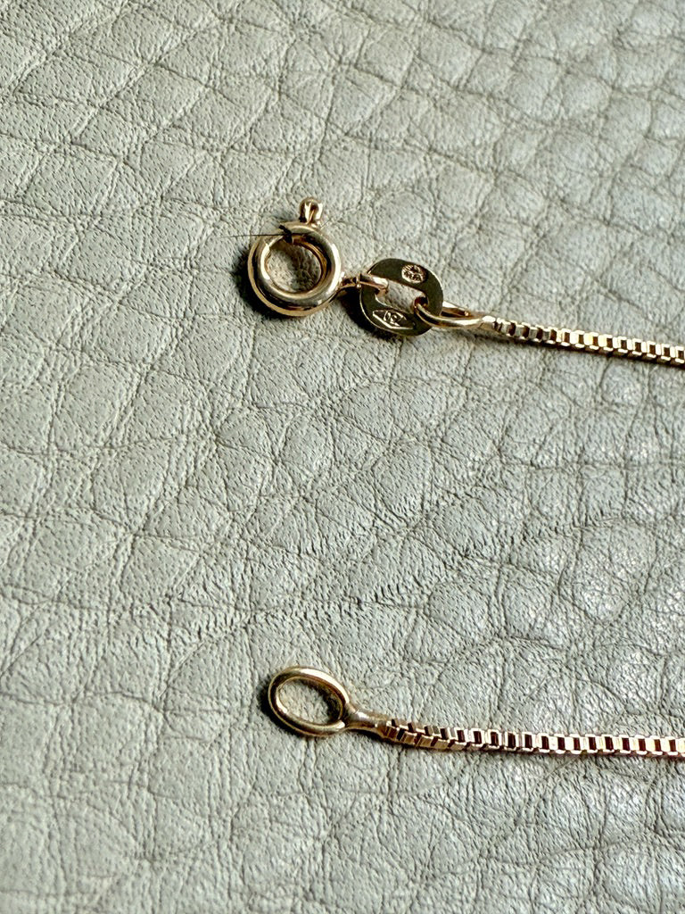 Gold necklace on a textured light gray surface