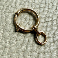 18k Gold antique bolt ring jewelry clasp piece on a textured light gray background