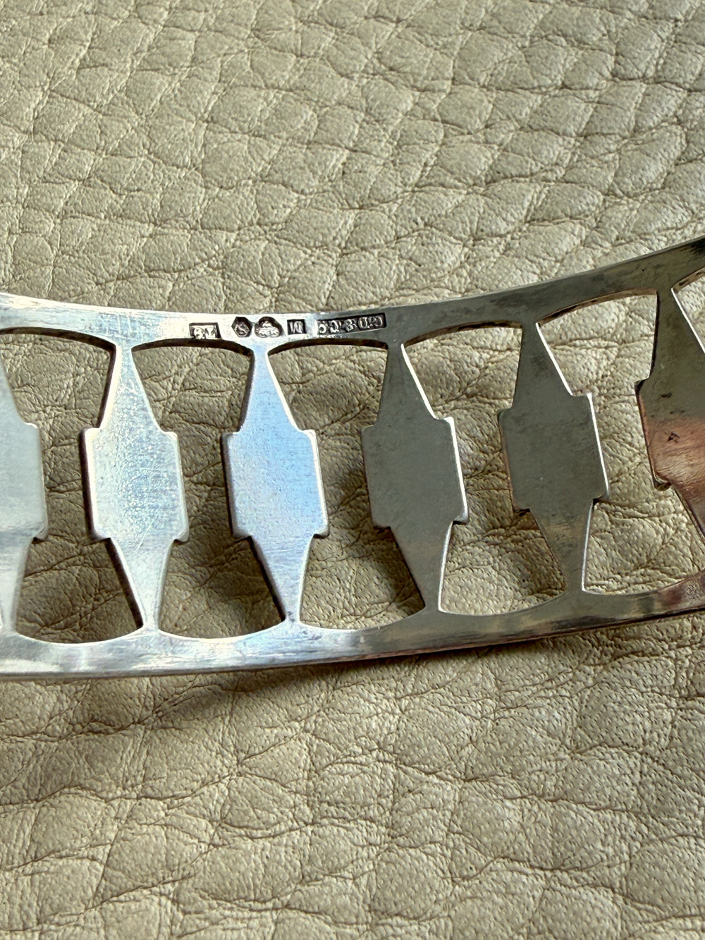 silver vintage bracelet detail with decorative elements on a textured beige surface