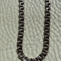 Silver chain necklace on a textured light gray surface